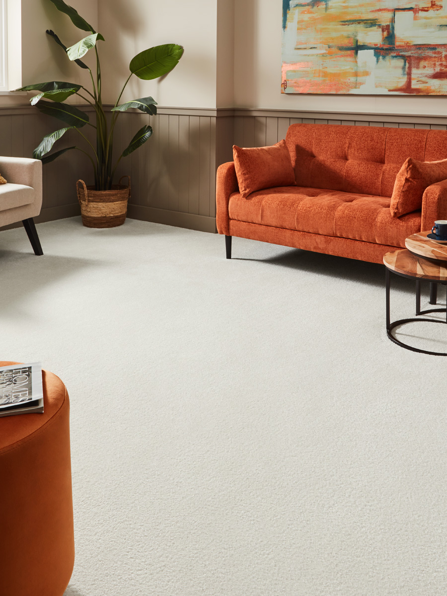 cream saxony carpet in living room with orange sofa
